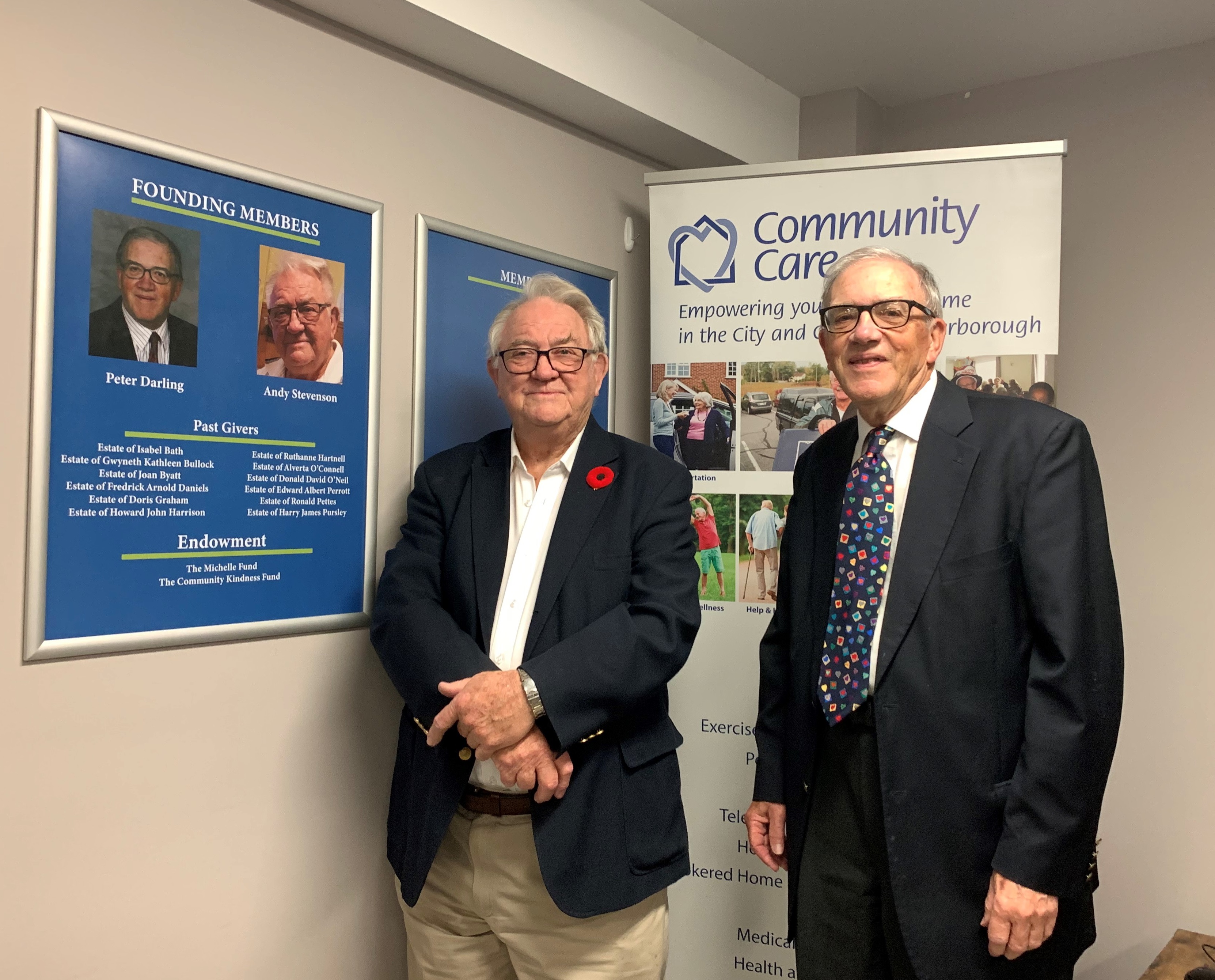 Andy Stevenson and Peter Darling standing next to the Circle of Care legacy Boards in CCP's Peterborough office