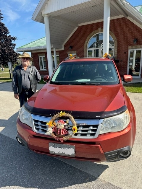 Volunteer Bill Sova standing with vehicle decorated for fall